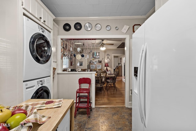 interior space with ornamental molding, ceiling fan, and stacked washer / dryer