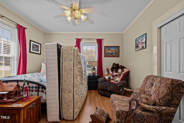 bedroom with ceiling fan, ornamental molding, and light hardwood / wood-style floors