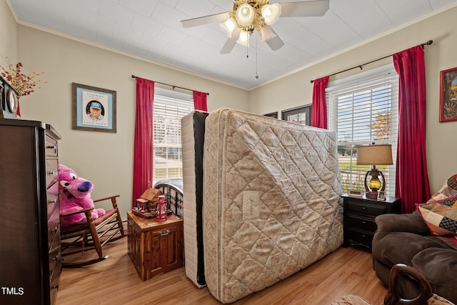 bedroom featuring ornamental molding, multiple windows, ceiling fan, and light hardwood / wood-style floors