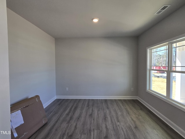 spare room featuring baseboards, visible vents, and dark wood-type flooring