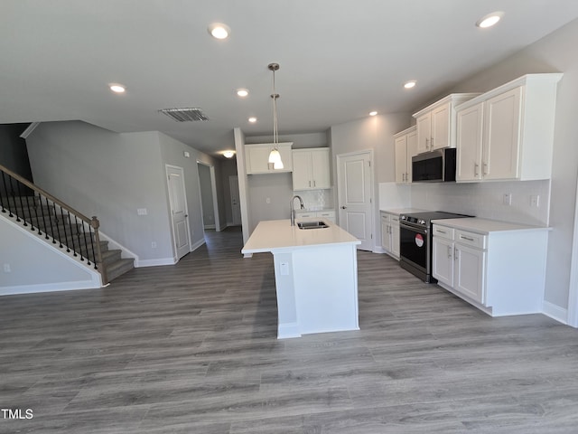 kitchen with appliances with stainless steel finishes, white cabinetry, a sink, and light wood finished floors