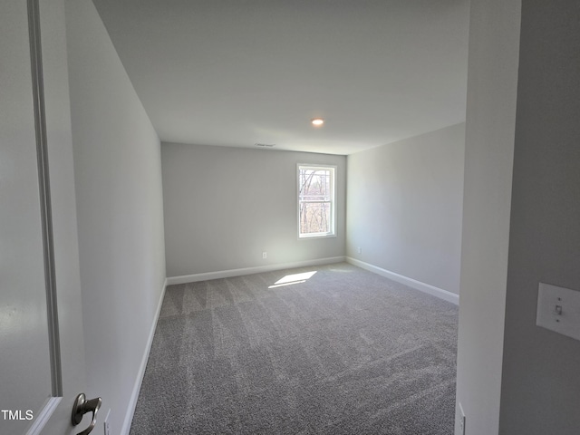 unfurnished room with carpet, visible vents, and baseboards