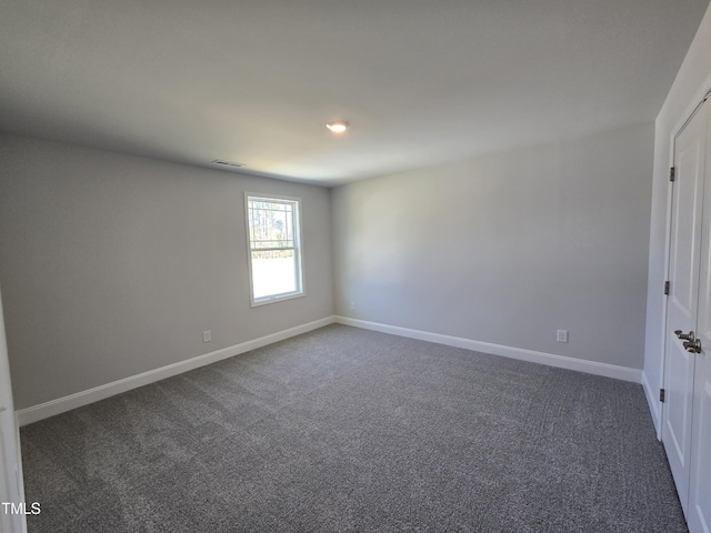 empty room featuring visible vents, baseboards, and dark colored carpet