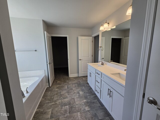 bathroom with double vanity, a garden tub, baseboards, and a sink