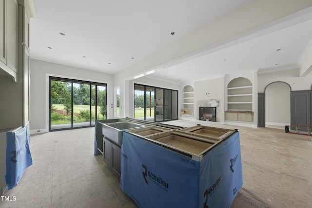 7000 N Ridge Dr, Raleigh, NC 27615 - kitchen with built in shelves, a glass covered fireplace, open floor plan, and a kitchen island with sink