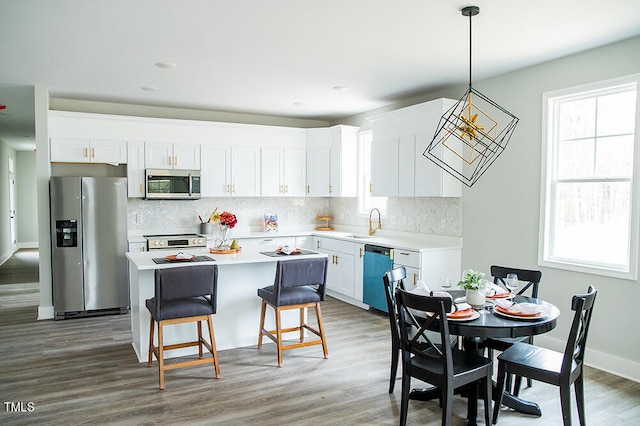 kitchen featuring white cabinetry, hanging light fixtures, stainless steel appliances, and dark hardwood / wood-style flooring