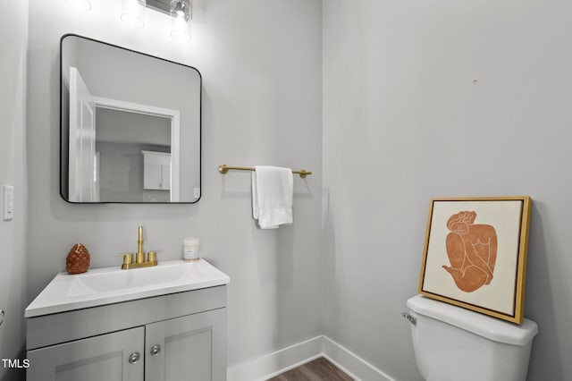 bathroom featuring toilet, vanity, baseboards, and wood finished floors