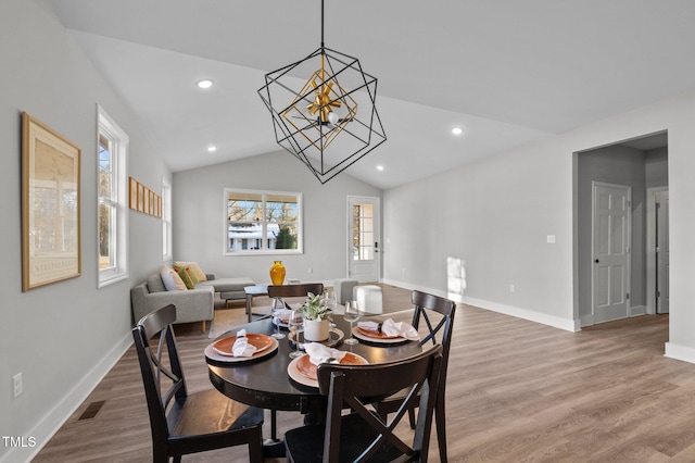 dining area with vaulted ceiling, baseboards, wood finished floors, and a chandelier