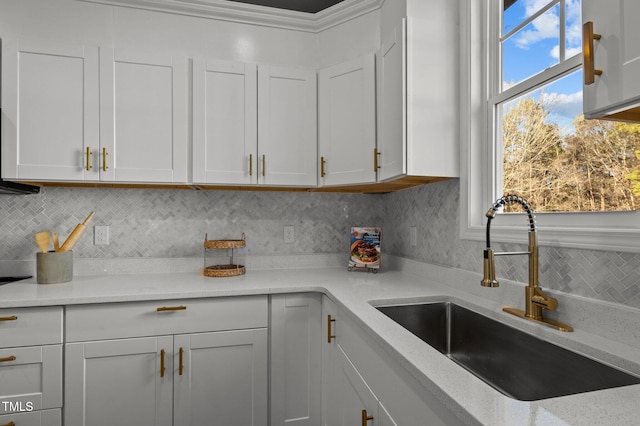 kitchen with light stone counters, a sink, and white cabinets