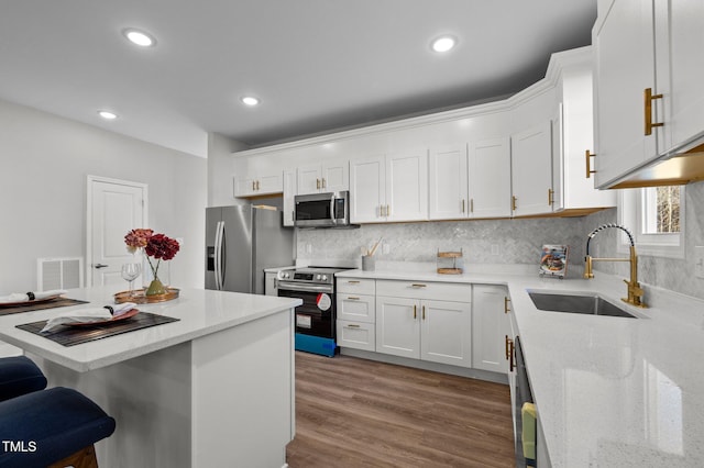 kitchen featuring stainless steel appliances, white cabinetry, a sink, and visible vents