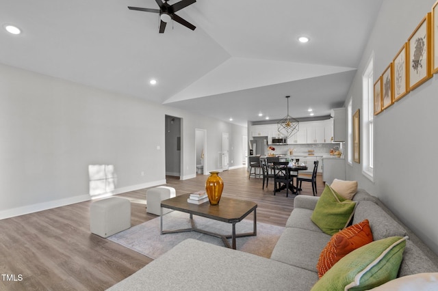 living area featuring recessed lighting, a ceiling fan, baseboards, vaulted ceiling, and light wood finished floors