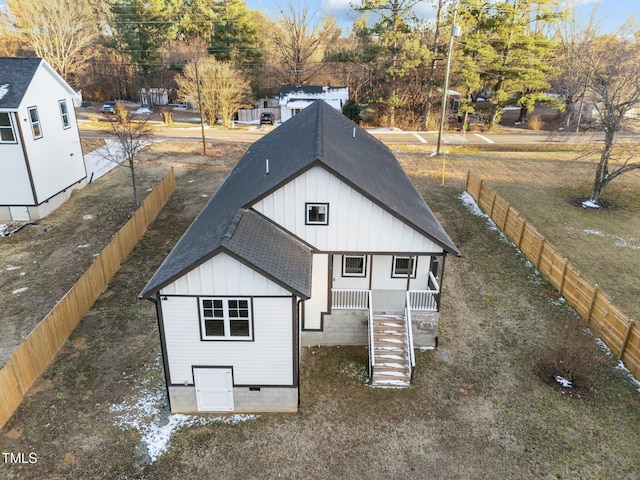 view of front of house featuring stairs, board and batten siding, roof with shingles, and fence