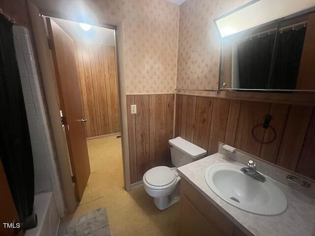 bathroom featuring wood walls, toilet, and vanity