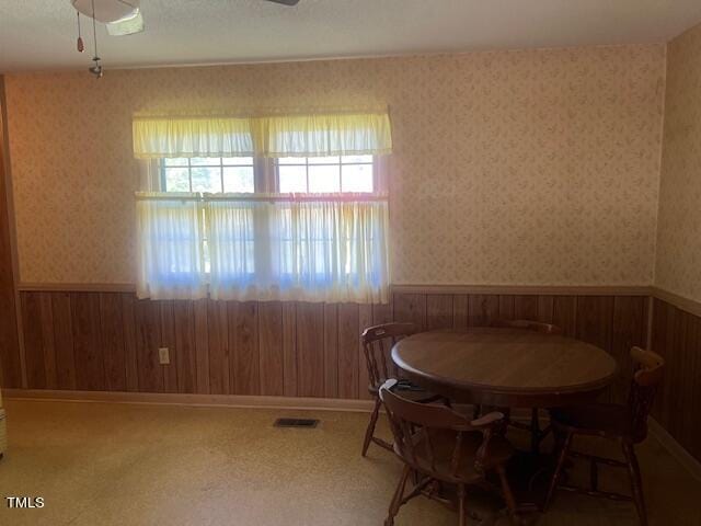 dining area featuring wood walls and ceiling fan