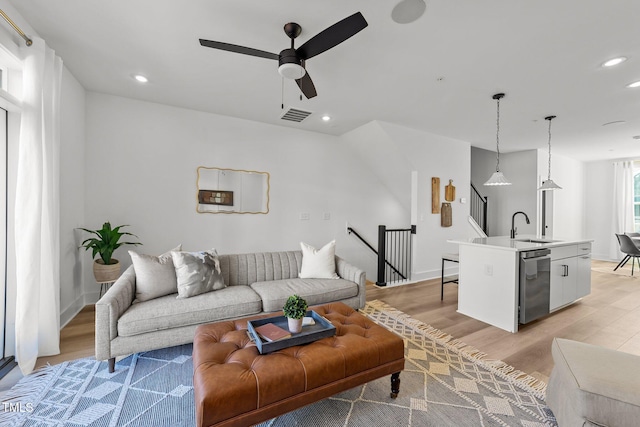 living room with sink, light wood-type flooring, and ceiling fan