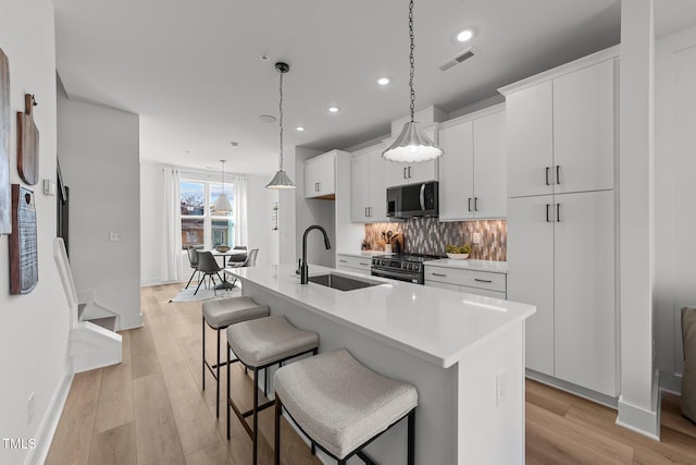 kitchen featuring appliances with stainless steel finishes, sink, white cabinetry, and a center island with sink