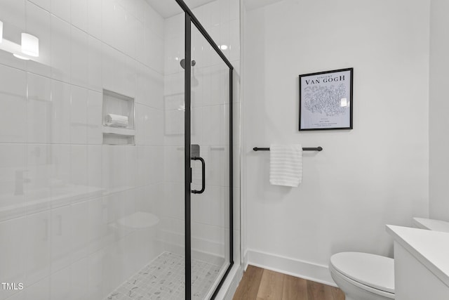 bathroom featuring toilet, vanity, a shower with shower door, and wood-type flooring