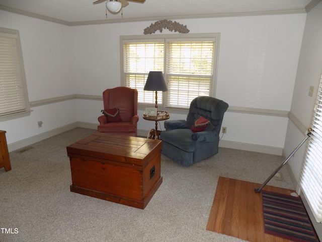 living area featuring crown molding, light carpet, and ceiling fan