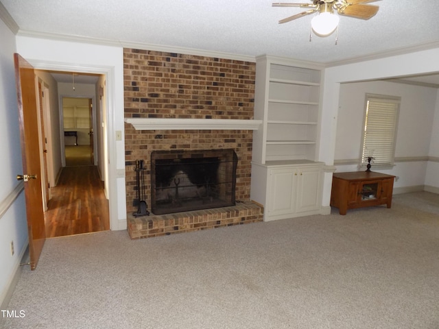 unfurnished living room with a textured ceiling, carpet flooring, a fireplace, built in shelves, and crown molding