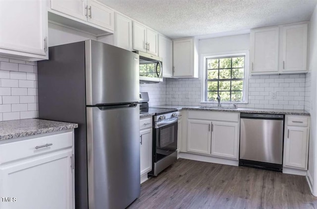 kitchen with stainless steel appliances, white cabinetry, hardwood / wood-style floors, and sink