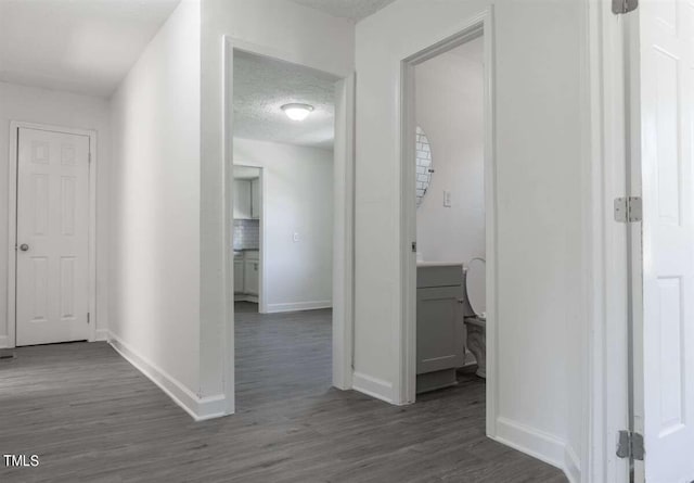 corridor with a textured ceiling and dark wood-type flooring