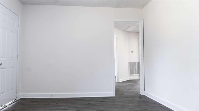 spare room with a textured ceiling and dark wood-type flooring