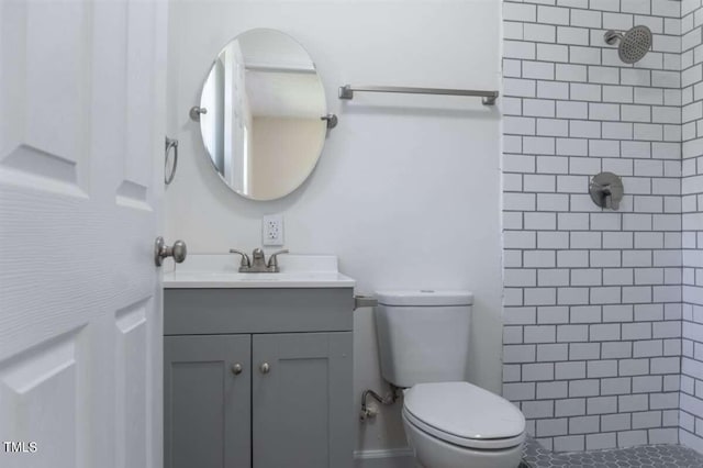 bathroom with tiled shower, vanity, and toilet