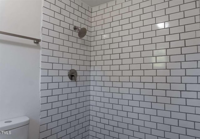 bathroom with a tile shower and toilet