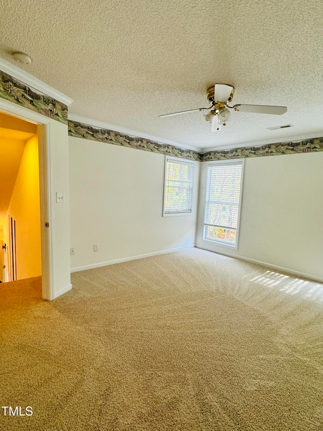 empty room with ceiling fan, a textured ceiling, crown molding, and carpet