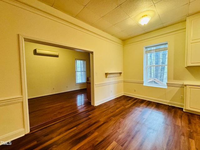 unfurnished dining area featuring a wall unit AC, a wealth of natural light, and dark hardwood / wood-style floors