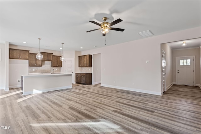 unfurnished living room with ceiling fan, ornamental molding, and light hardwood / wood-style flooring