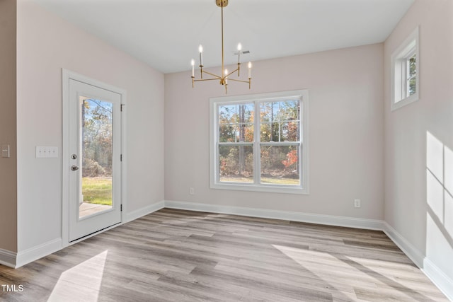 unfurnished dining area with light hardwood / wood-style floors and a notable chandelier