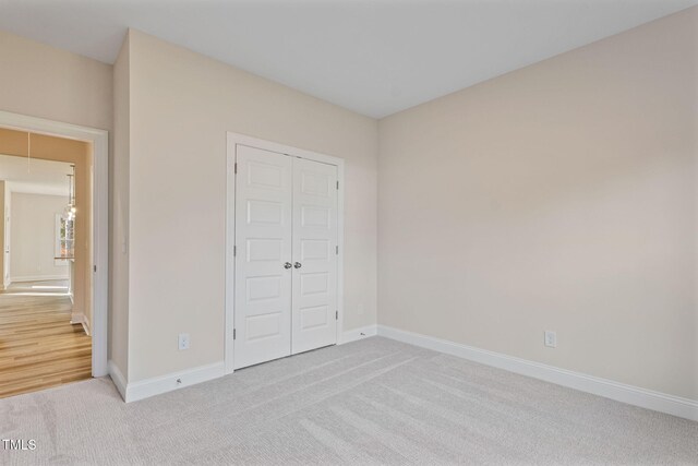 unfurnished bedroom featuring light carpet and a closet