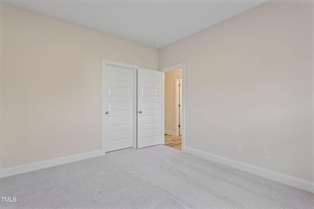 unfurnished bedroom featuring light carpet and a closet