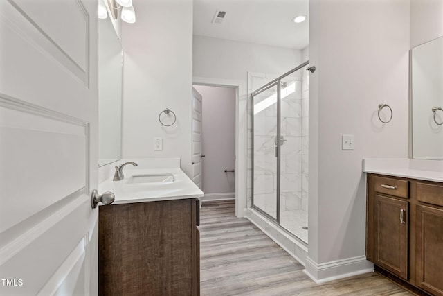 bathroom featuring hardwood / wood-style floors, vanity, and a shower with shower door