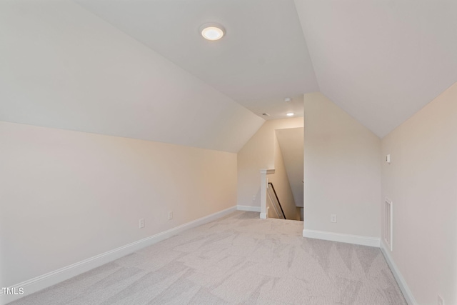 bonus room with light colored carpet and vaulted ceiling