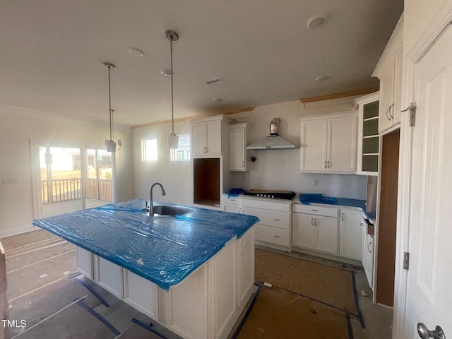 kitchen with gas cooktop, wall chimney exhaust hood, a kitchen island with sink, sink, and white cabinetry