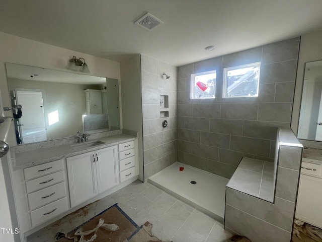 bathroom with tiled shower, vanity, and tile patterned flooring