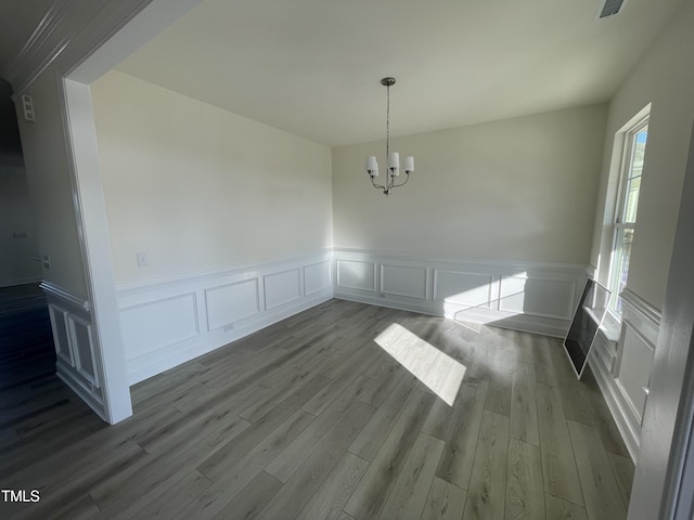 unfurnished dining area featuring hardwood / wood-style floors and a notable chandelier