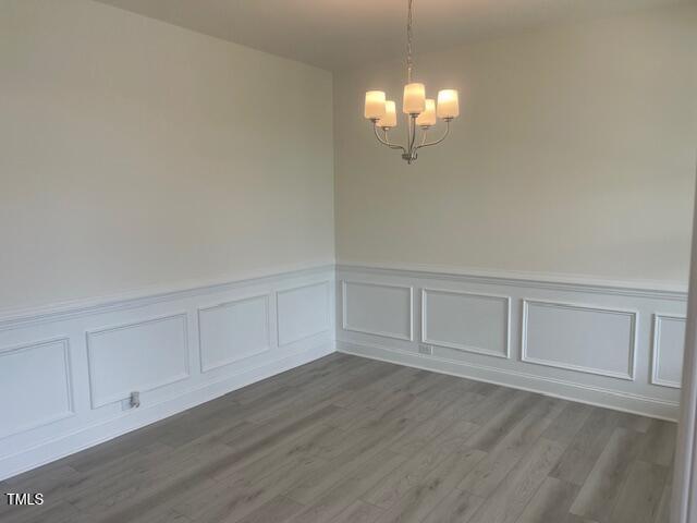 1528 Maelyn Way, Fuquay Varina, NC 27526 - unfurnished dining area featuring a chandelier, a decorative wall, wainscoting, and dark wood-style floors