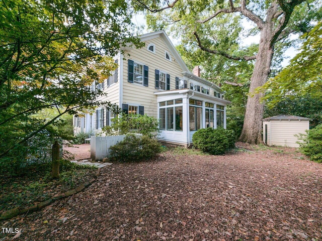 rear view of house featuring a shed and a sunroom