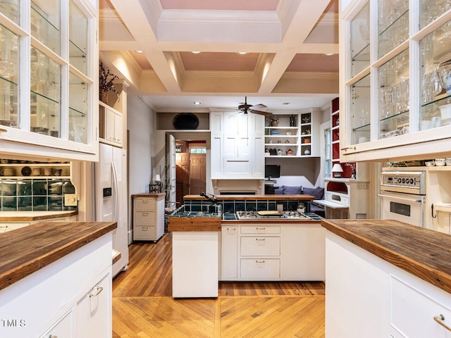 kitchen featuring beam ceiling, ceiling fan, coffered ceiling, white refrigerator with ice dispenser, and white cabinets