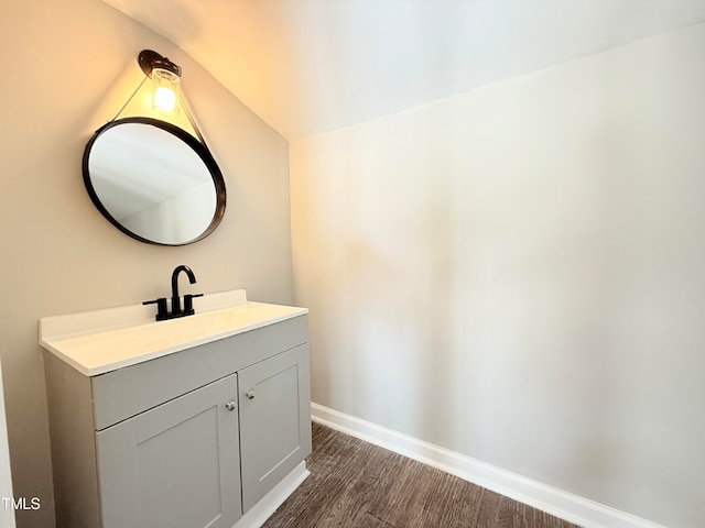 bathroom featuring vanity, lofted ceiling, and wood-type flooring