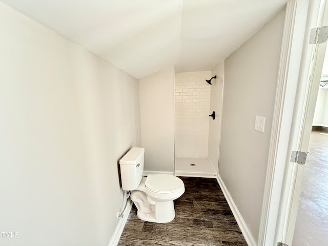 bathroom with toilet, lofted ceiling, wood-type flooring, and tiled shower