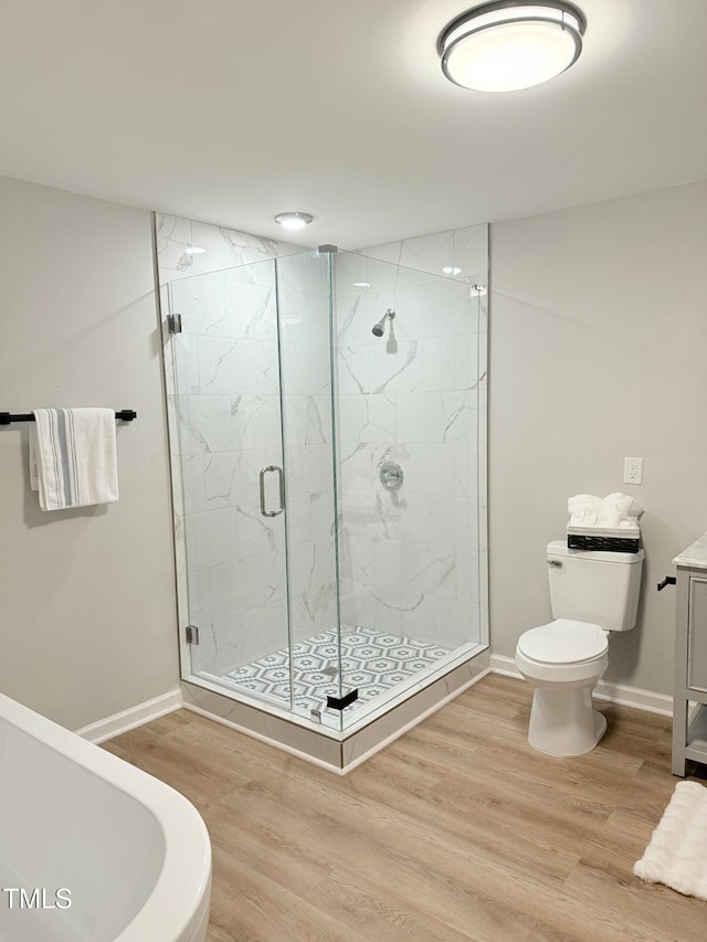 bathroom with hardwood / wood-style floors, a shower with door, and toilet