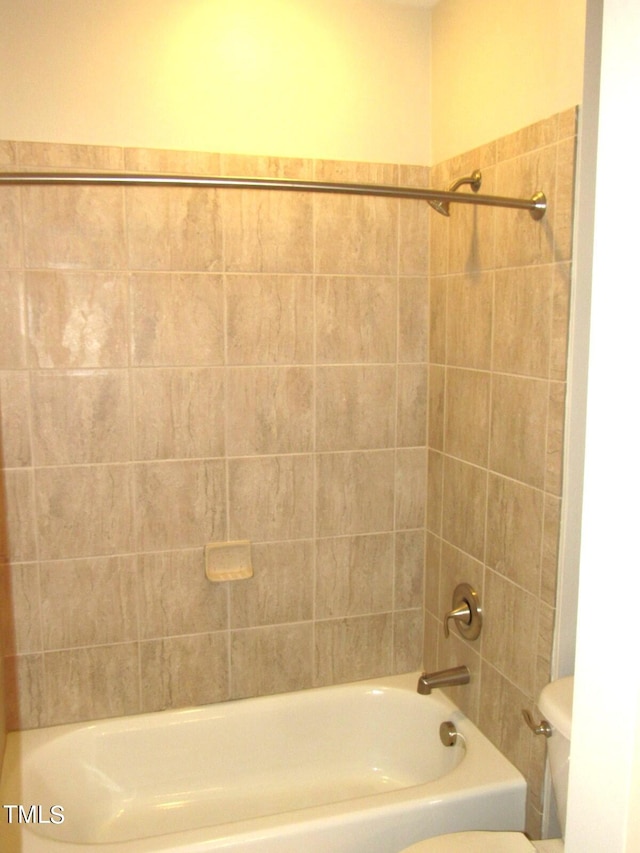 bathroom with tiled shower / bath combo and toilet