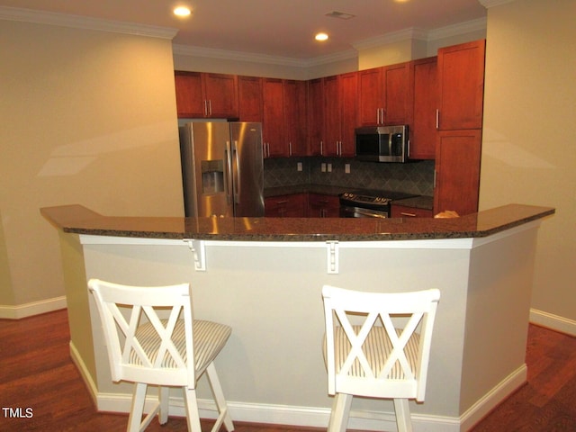 kitchen with backsplash, a breakfast bar area, stainless steel appliances, and dark hardwood / wood-style floors