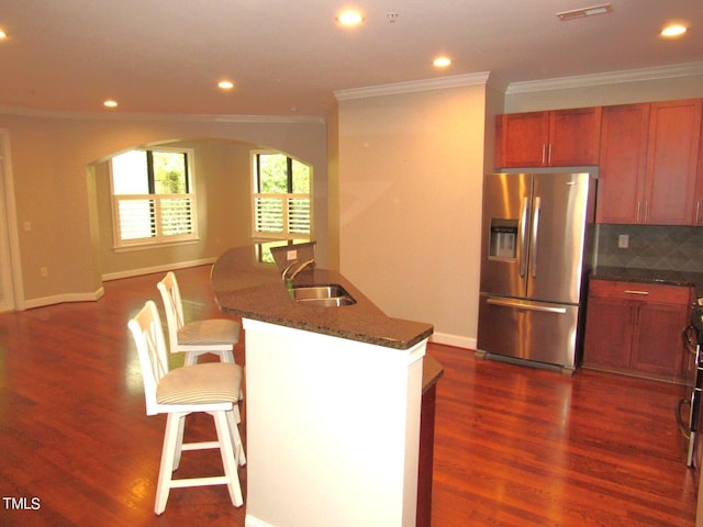 kitchen featuring stainless steel refrigerator with ice dispenser, sink, a breakfast bar area, dark hardwood / wood-style floors, and an island with sink