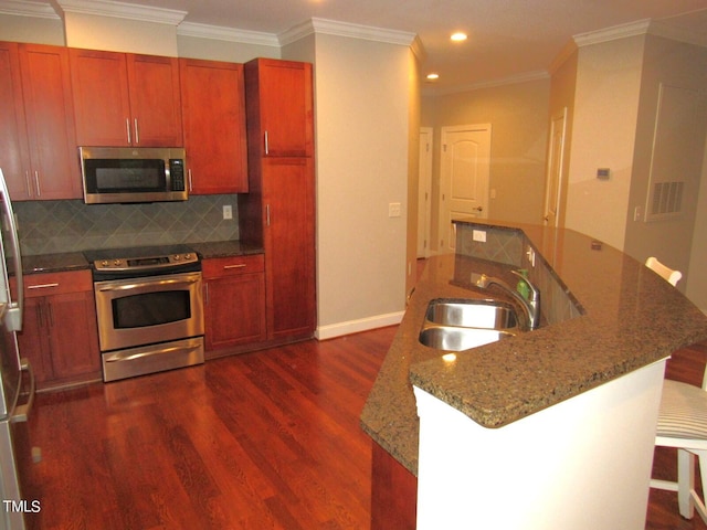 kitchen featuring sink, appliances with stainless steel finishes, dark hardwood / wood-style floors, a kitchen breakfast bar, and decorative backsplash