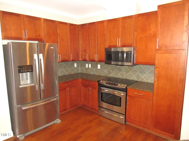 kitchen with hardwood / wood-style flooring, tasteful backsplash, appliances with stainless steel finishes, and dark stone counters